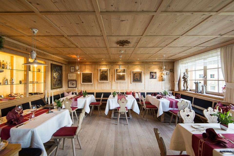 Ristorante dell’Hotel Cappella con stube alpina in legno, tavoli apparecchiati e opere d’arte