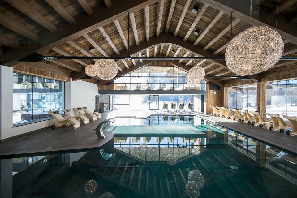 Piscina interna riscaldata dell’Hotel Cappella con architettura in legno e ampie vetrate panoramiche